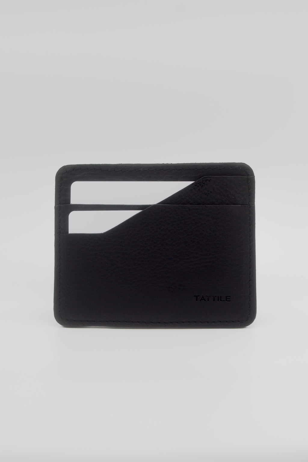 A minimalist black leather card holder wallet with a textured pebbled finish, featuring two card slots on the front and the debossed brand name 'TATILE' in the bottom right corner, set against a light gray background.