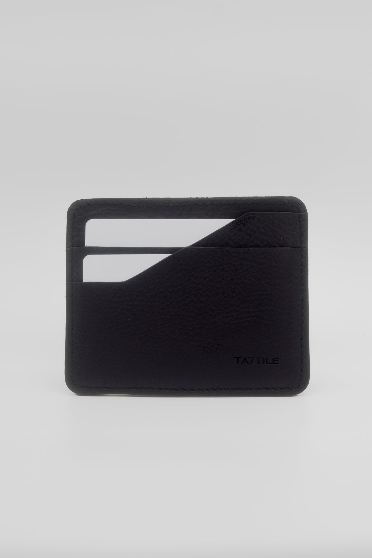 A minimalist black leather card holder wallet with a textured pebbled finish, featuring two card slots on the front and the debossed brand name 'TATILE' in the bottom right corner, set against a light gray background.